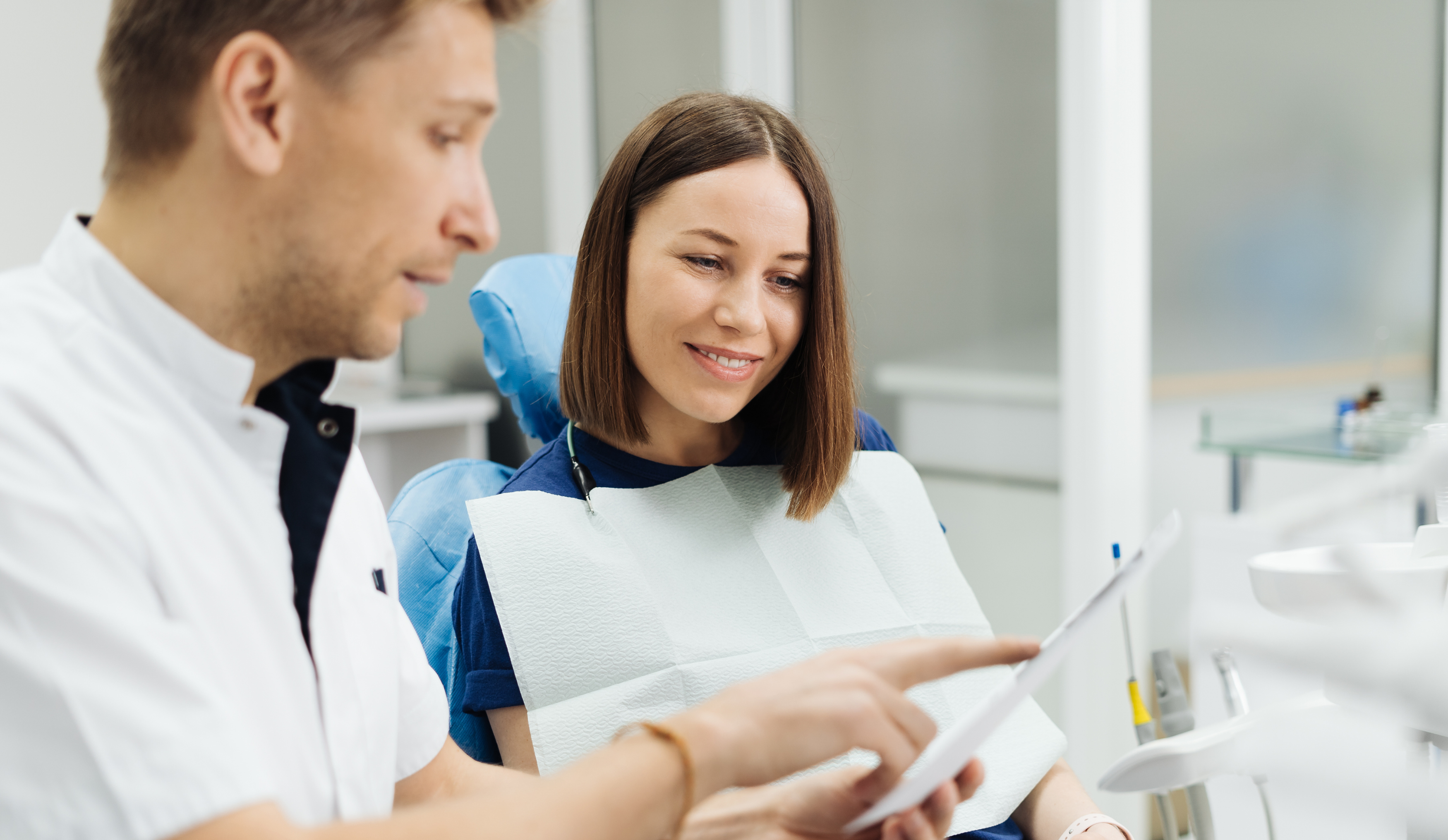 Woman sitting in dentist chair talking to the dentist about work that need to be done.