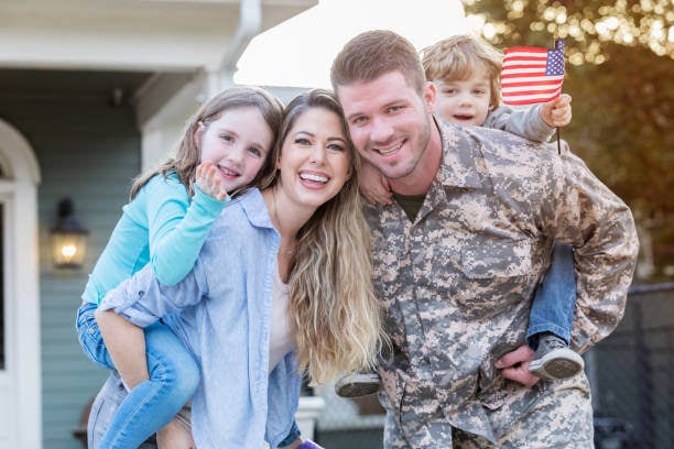 U.S. military man and his spouse holding up their son and daughter