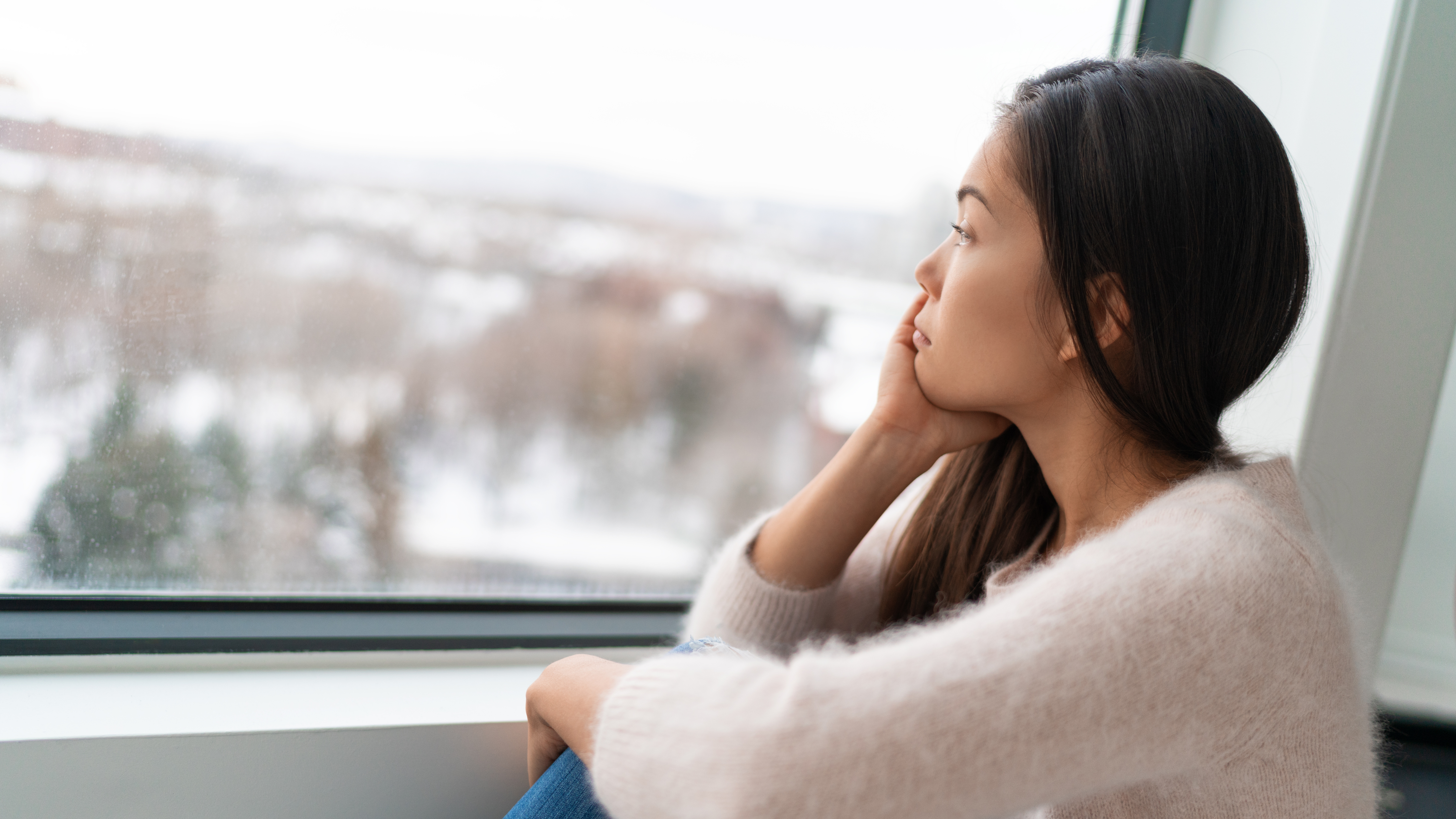 Woman staring out the window dealing with winter weather.